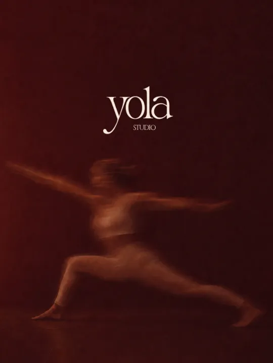 Une élève en posture du guerrier, silhouette floue par le mouvement sur le fond rouge sombre de la salle, sous le logo yola studio.